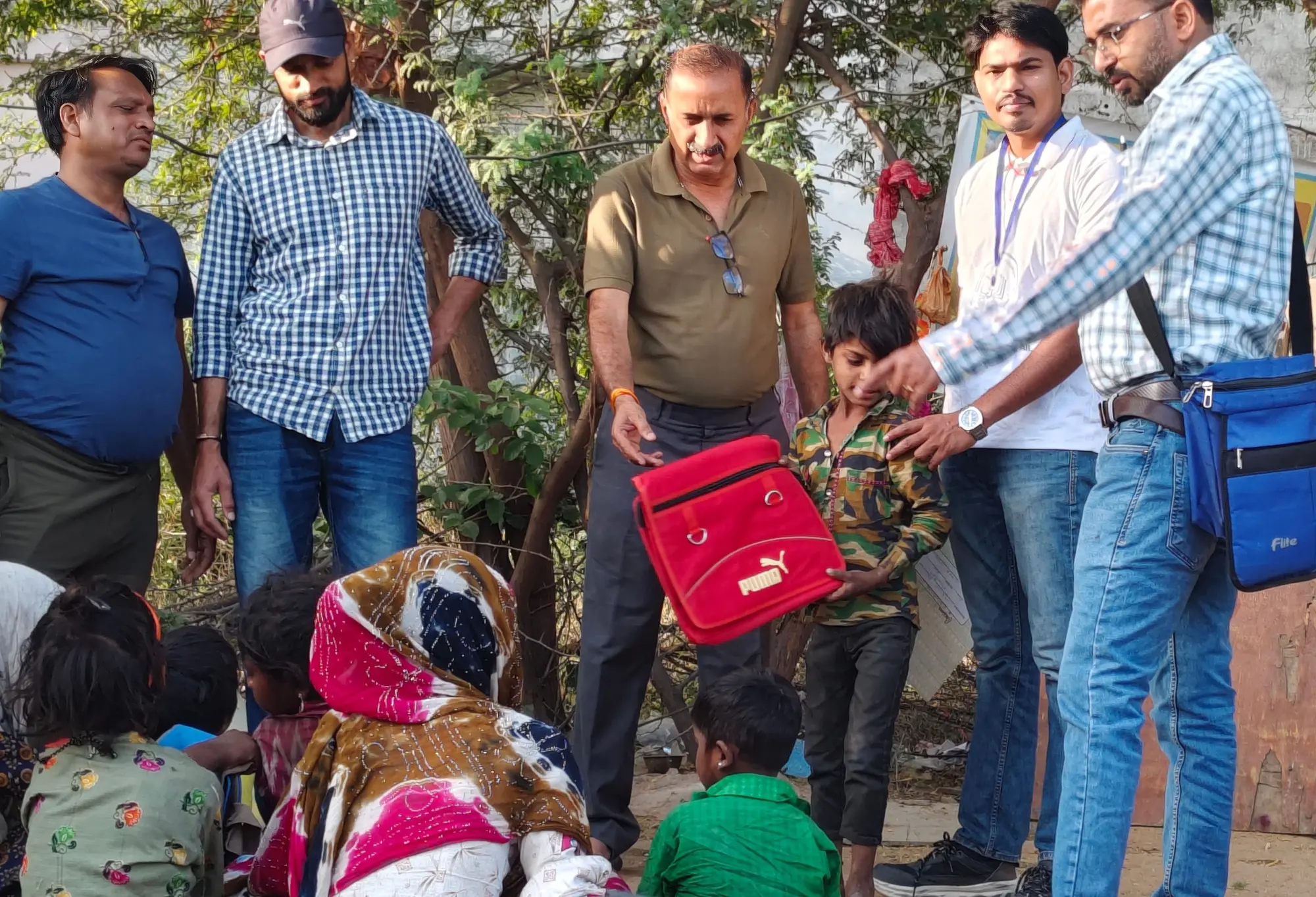 A foundation volunteer handing a blue school bag directly to a child during the April material drive.